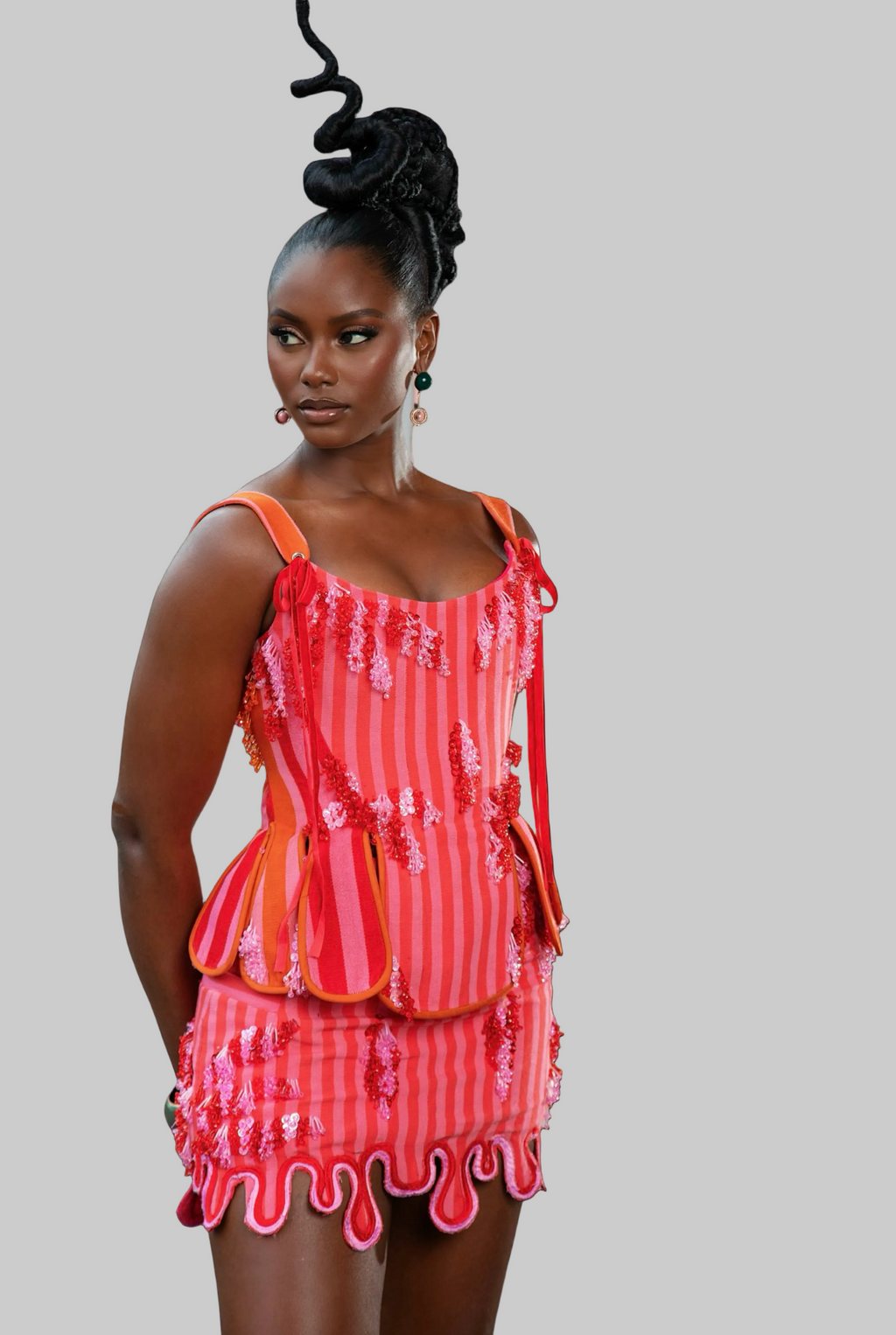 Woman wearing a red and orange dress with ruffled details on a white background